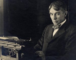 Photograph of Carl Sandburg sitting with his typewriter at his home in Illinois, circa 1917-1918.