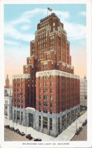 A painted vertical postcard illustrates the Milwaukee Gas Light Company building on a street corner. The stepped tower faces slightly to the left. An American flag stands atop the building. Cars of different colors are parked on the street around the tower. The sky is colored in orange which gradually turns blue.