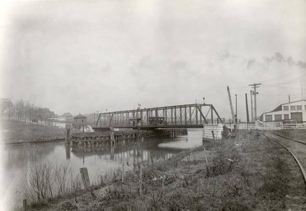 A grayscale wide shot of the Lincoln Avenue Bridge over the Kinnickinnic River connecting the two banks.