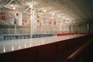Interior photograph of the Pettit National Ice Center with international flags hanging from the rafters.