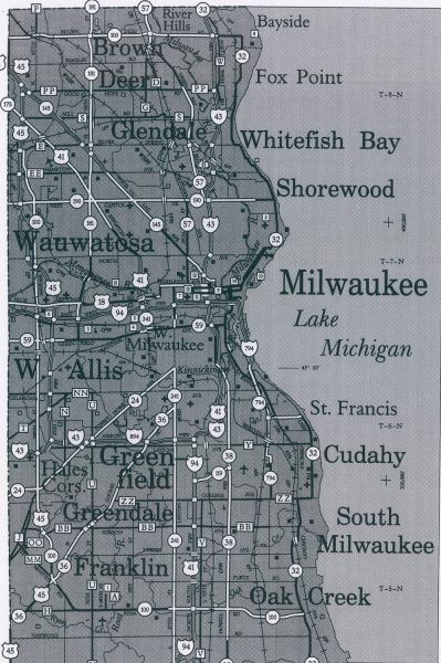 A map of Milwaukee County shows the areas of the suburban municipalities that surround the city of Milwaukee. Each area is marked by the municipalities' names written in large fonts. The map also displays lines symbolizing various types of roadways, railroads, public facilities, and the state, county, and civil town boundaries, among others.