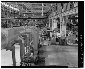 This 1988 photograph provides an interior view of the American Brass Company plant in Kenosha. The employee at the center of the photo adjusted the rolls necessary to operate the mills.