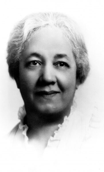 Grayscale headshot of Mabel Raimey smiling in a blouse with eyes looking slightly to the right.