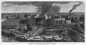 A drawing of the Milwaukee Cement Company in grayscale illustrates a bird's eye view of the building complex. Smoke billows from a giant structure in the center and two chimneys in the far background. Below the massive structure is lower ground with railway tracks and people working with horses. Surrounding the area in the left background and foreground is a body of water. A group of railroad cars on a bridge over the river steams towards the land in the far background.