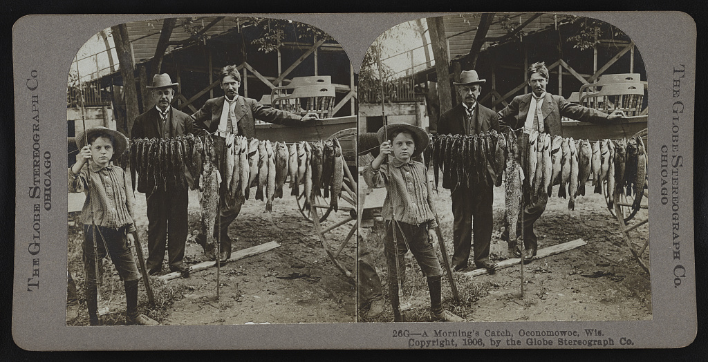 In this photograph from between 1900 and 1910, two men and a young boy stand next to the line of fish they caught one morning in Oconomowoc.