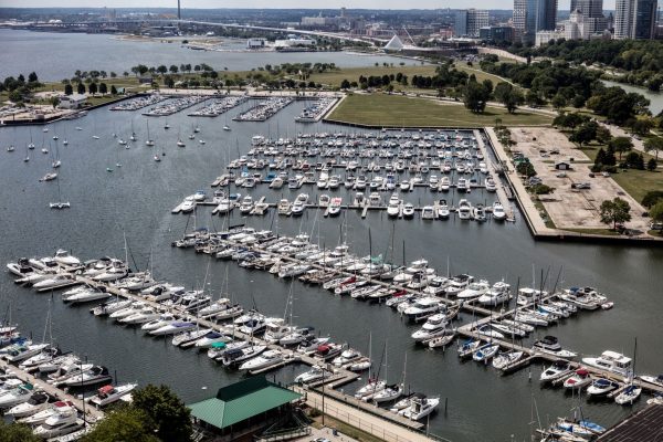 Aerial shot of rows of boats moored in the marina in Lake Michigan. In the background is the Milwaukee landscape with buildings on the far right and a long bridge on the far left.
