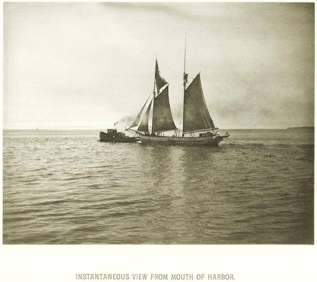 A tugboat pulls a sailing ship out of the Milwaukee Harbor toward Lake Michigan in 1885.